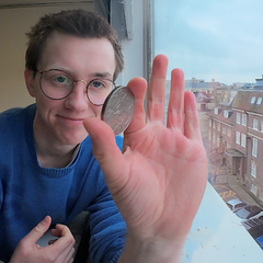 Nathaniel Wright holding a coin, with a university building in the background