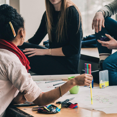 People sitting around table with paper and pens